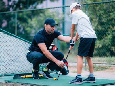 Golf Lessons. Golf instructor giving game lesson to a young boy.